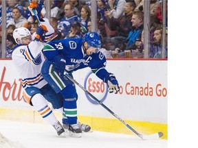Vancouver Canucks captain Henrik Sedin keeps the puck from Edmonton Oilers Taylor Hall Saturday at Rogers Arena.