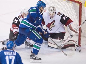 Vancouver Canucks center Bo Horvat (53) puts a shot past Arizona Coyotes goalie Louis Domingue (35) as Arizona Coyotes defenseman Michael Stone (26) looks on during second period NHL action in Vancouver, B.C. Monday, Jan. 4, 2016.