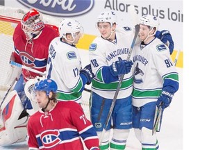 Vancouver Canucks center Jared McCann (91) celebrates with teammates Vancouver Canucks right wing Jake Virtanen (18) and Vancouver Canucks right wing Radim Vrbata (17) after scoring the second goal against Montreal Canadiens goalie Mike Condon (39) as Montreal Canadiens defenseman Tom Gilbert during first period NHL action Monday, Nov. 16, 2015 in Montreal.