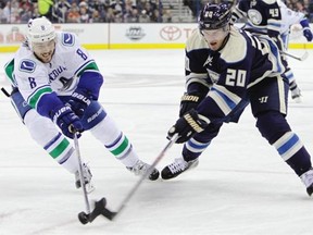 Vancouver Canucks’ Christopher Tanev, left, and Columbus Blue Jackets’ Brandon Saad reach for a loose puck during the second period of an NHL hockey game Tuesday, Nov. 10, 2015, in Columbus, Ohio.