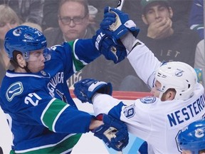 Vancouver Canucks defenseman Ben Hutton (27) fights for control of the puck with Tampa Bay Lightning defenseman Nikita Nesterov (89) during second period NHL action Vancouver, B.C. Saturday, Jan. 9, 2016.