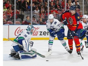 Vancouver Canucks defenseman Ben Hutton (27) looks on as Vancouver Canucks goaltender Ryan Miller (30) defends the net against the shot by Florida Panthers forward Jaromir Jagr (68) during the first period of an NHL hockey game, Sunday, Dec. 20, 2015, in Sunrise, Fla.