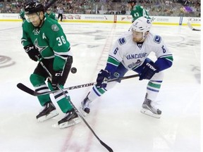 Vancouver Canucks defenseman Yannick Weber (6) and Dallas Stars center Vernon Fiddler (38) skate for  control of the puck during the first period of an NHL hockey game Thursday, Oct. 29, 2015, in Dallas.