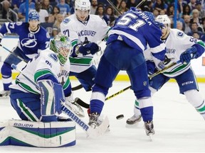 Vancouver Canucks goalie Jacob Markstrom (25), of Sweden, makes a save on a shot as defenseman Ben Hutton (27) keeps Tampa Bay Lightning left wing Mike Angelidis (10) from a rebound during the first period of an NHL hockey game Tuesday, Dec. 22, 2015, in Tampa, Fla.