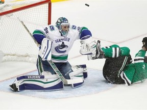 Vancouver Canucks goalie Ryan Miller (30) blocks a shot as Dallas Stars center Tyler Sequin slides on the ice during the first period of an NHL hockey game Friday, Nov. 27, 2015, in Dallas.