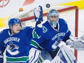 Vancouver Canucks’ goalie Ryan Miller, right, watches the puck as Alex Burrows reaches for it during the second period of an NHL hockey game against the Colorado Avalanche in Vancouver, B.C., on Sunday February 21, 2016.
