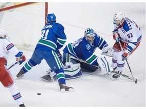 Vancouver Canucks’ goalie Ryan Miller stops New York Rangers’ Keith Yandle (93) as teammate Kevin Hayes waits for the rebound while Jared McCann (91) defends during second period NHL hockey action, in Vancouver, on Wednesday, Dec. 9, 2015.