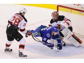 Vancouver Canucks Jannik Hansen  #36, is sent fllying infront of  the New Jersey Devils Cory Schneider #35 , at Rogers Arena in Vancouver  November 22, 2015.