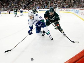 Vancouver Canucks right wing Jannik Hansen (36), of Denmark, and Minnesota Wild center Mikko Koivu (9), of Finland, chase the puck during the second period of an NHL hockey game in St. Paul, Minn., Wednesday, Nov. 25, 2015.
