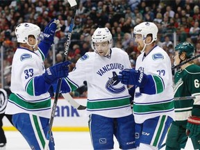 Vancouver Canucks right wing Radim Vrbata, center, of the Czech Republic, celebrates with teammates Daniel Sedin, right, of Sweden, and Henrik Sedin, left, of Sweden, after scoring on Minnesota Wild goalie Devan Dubnyk during the second period of an NHL hockey game in St. Paul, Minn., Wednesday, Nov. 25, 2015.