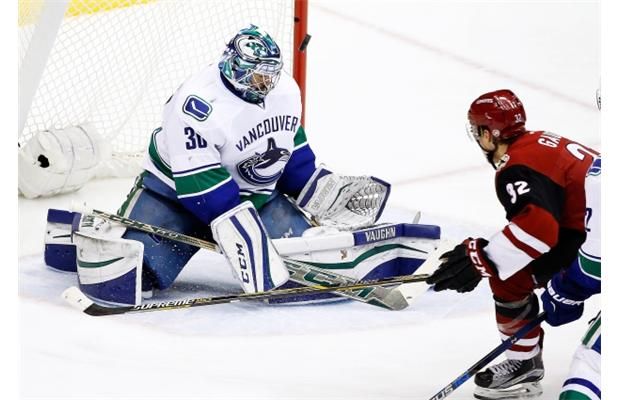 Vancouver Canucks’ Ryan Miller, left, makes a save on a shot by Arizona Coyotes’ Tyler Gaudet (32) during the second period of an NHL hockey game Wednesday, Feb. 10, 2016, in Glendale, Ariz.
