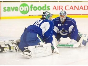 Vancouver goaltenders Ryan Miller and Jakob Markstrom, right, chat while doing a stretching exercise on ice.