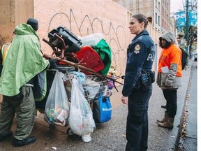 A Vancouver Police officer speaks with a homeless man on Hastings Street in Vancouver on Monday Nov. 16, 2015. Dozens of homeless people in Vancouver’s Downtown Eastside are being displaced by a heavy police presence during the city’s push to relocate illegal sidewalk vendors to sanctioned markets, advocates say.