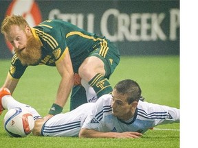 Vancouver Whitecaps forward Octavio Rivero is taken to the pitch by Portland Timbers Nat Borchers during Sunday’s 2-0 loss at BC Place that saw the Whitecaps eliminated from the MLS playoffs.