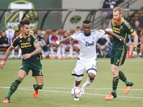 Vancouver Whitecaps midfielder Gershon Koffie (28) tries to get past Portland Timbers defender Liam Ridgewell (24) and defender Nat Borchers (7) during the first half of an MLS western conference semifinal soccer match in Portland, Ore., Sunday, Nov. 1, 2015.