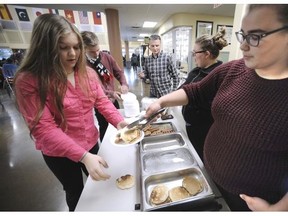 Victoria Csillag and Bryanne Lane (right) serve breakfast with Dennis Hemminger (centre) to some of the 240 students who participate twice a week at Maple Ridge secondary.