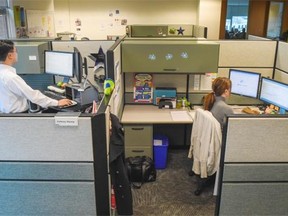 Webmaster Anthony Waung (left) at Pacific Blue Cross in Burnaby, works at his sit-stand desk.