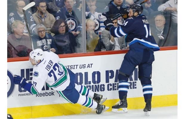 Winnipeg Jets’ Anthony Peluso (14) checks Vancouver Canucks’ Alexander Edler (23) during first period NHL action in Winnipeg on Wednesday, November 18, 2015.