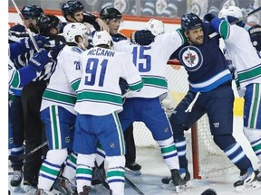 Winnipeg Jets’ Dustin Byfuglien battles with Vancouver Canucks’ Derek Dorsett, centre, and Jannik Hansen, right, during the Jets’ 4-1 win.