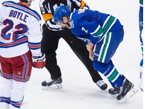 New York Rangers’ Dan Boyle (22) watches as Vancouver Canucks’ Dan Hamhuis is helped off the ice by referee Ian Walsh after being struck in the mouth by the puck.