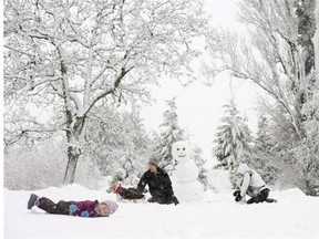 A young family plays in the snow in Queen Elizabeth Park in Vancouver in this file photo.