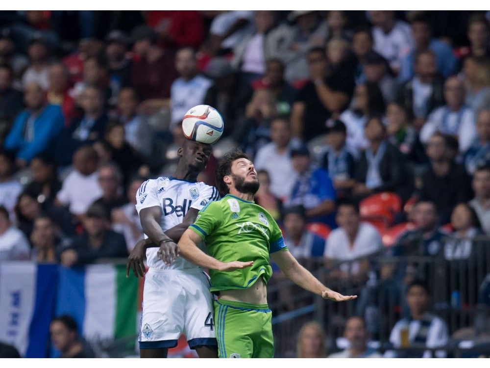 Vancouver Whitecaps' Pa-Modou Kah, left, of Norway, gets his head on the ball behind Seattle Sounders' Brad Evans during the second half of an MLS soccer game in Vancouver, B.C., on Saturday September 19, 2015. THE CANADIAN PRESS/Darryl Dyck