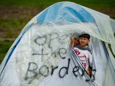 Two boys peer out from inside a tent marked with the slogan "Open the Border"at a makeshift camp occupied by migrants and refugees at the Greek-Macedonian border near the village of Idomeni on March 24, 2016.  The UN refugee agency harshly criticized an EU-Turkey deal on curbing the influx of migrants to Greece, saying reception centers had become "detention facilities", and suspended some activities in the country. The EU and Ankara struck a deal on Friday aiming to cut off the sea crossing from Turkey to the Greek islands that enabled 850,000 people to pour into Europe last year, many of them fleeing the brutal war in Syria. ANDREJ ISAKOVIC/AFP/Getty Images