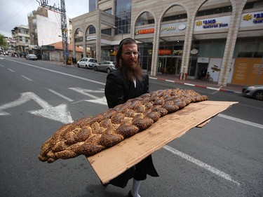 An ultra-Orthodox Jewish man carries a huge bread on a street in the central Israeli city of Bnei Brak on March 24, 2016 during the feast of Purim. The carnival-like Purim holiday is celebrated with parades and costume parties to commemorate the deliverance of the Jewish people from a plot to exterminate them in the ancient Persian empire 2,500 years ago, as recorded in the Biblical Book of Esther. MENAHEM KAHANA/AFP/Getty Images