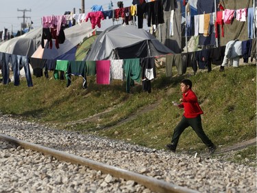 A migrant boy runs at the train tracks in a makeshift refugee camp at the northern Greek border point of Idomeni, Greece, Wednesday, March 30, 2016. The flow of migrants to the Greek islands, meanwhile, seems to be on the rise again as weather warms.