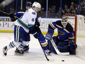 Vancouver Canucks' Jake Virtanen, left, controls the puck as St. Louis Blues goalie Brian Elliott defends during the first period of an NHL hockey game Friday, March 25, 2016, in St. Louis.