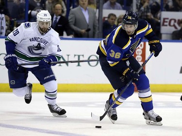 St. Louis Blues' Troy Brouwer, right, controls the puck as Vancouver Canucks' Chris Higgins watches during the second period of an NHL hockey game Friday, March 25, 2016, in St. Louis. (AP Photo/Jeff Roberson)