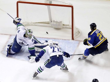 St. Louis Blues' Kyle Brodziak, right, scores past Vancouver Canucks goalie Jacob Markstrom, left and defenseman Ben Hutton (27) during the first period of an NHL hockey game Friday, March 25, 2016, in St. Louis. (AP Photo/Jeff Roberson)