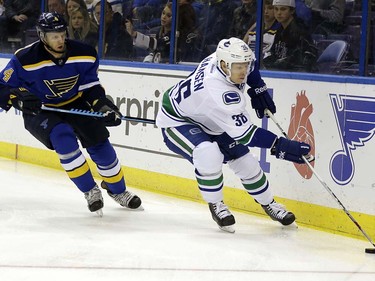 Vancouver Canucks' Jannik Hansen, right, of Denmark, controls the puck as St. Louis Blues' Carl Gunnarsson, of Sweden, watches during the first period of an NHL hockey game Friday, March 25, 2016, in St. Louis. (AP Photo/Jeff Roberson)