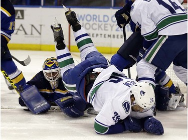 Vancouver Canucks' Emerson Etem, right, flips over St. Louis Blues goalie Brian Elliott while chasing after a loose puck during the first period of an NHL hockey game Friday, March 25, 2016, in St. Louis. (AP Photo/Jeff Roberson)