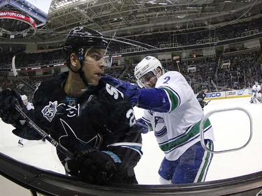 San Jose Sharks right wing Joonas Donskoi (27) is checked into the boards by Vancouver Canucks defenseman Dan Hamhuis (2) during the first period of an NHL hockey game Thursday, March 31, 2016, in San Jose, Calif. (AP Photo/Tony Avelar)
