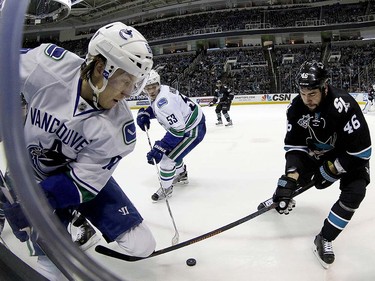 San Jose Sharks' Roman Polak (46) battles for the puck against Vancouver Canucks' Markus Granlund, left, of Finland, and Bo Horvat (53) during the second period of an NHL hockey game Thursday, March 31, 2016, in San Jose, Calif. (AP Photo/Tony Avelar)
