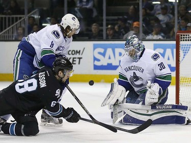 Vancouver Canucks goalie Ryan Miller (30) blocks a shot from San Jose Sharks right wing Melker Karlsson (68) during the first period of an NHL hockey game Thursday, March 31, 2016, in San Jose, Calif. Canucks' Chris Tanev (8) defends. (AP Photo/Tony Avelar)