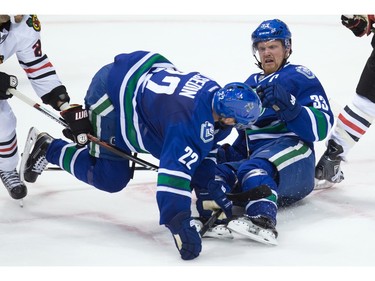 Vancouver Canucks' Daniel Sedin, left, is tripped up in front of his twin brother Henrik Sedin, both of Sweden, during the second period of an NHL hockey game against the Chicago Blackhawks in Vancouver, B.C., on Sunday March 27, 2016.