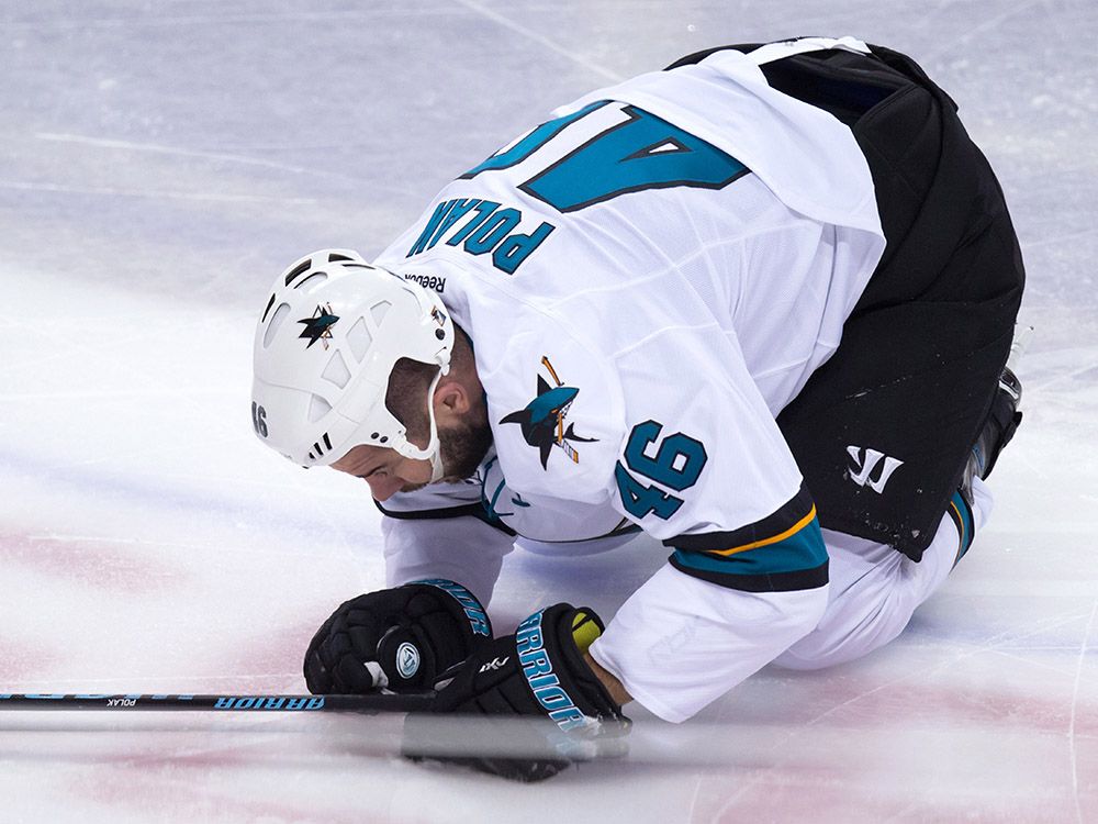 San Jose Sharks' Roman Polak, of the Czech Republic, kneels on the ice after being hit by Vancouver Canucks' Jake Virtanen during the second period of an NHL hockey game in Vancouver, B.C., on Tuesday March 29, 2016. THE CANADIAN PRESS/Darryl Dyck