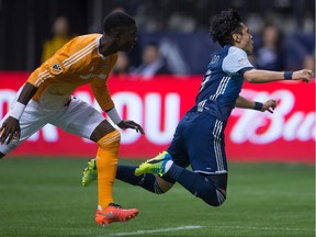 Vancouver Whitecaps Masato Kudo, right, is apparently tripped-up by Houston Dynamo's Jalil Anibaba during the first half in Vancouver on March 26.