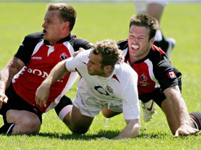 Canada's Matt King, left, and John Cannon, right, tackle England's James Simpson-Daniel during Churchill Cup rugby action in Edmonton on June 19, 2005. Former Canadian rugby international Cannon has died at 35 of a suspected heart attack. Cannon passed away early Saturday, according to his father.