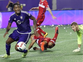 Orlando City SC's Cyle Larin, left, moves the ball in front of fallen Chicago goalkeeper Matt Lampson, right, during an MLS game on Friday, March 11, 2016 in Orlando, Fla.
