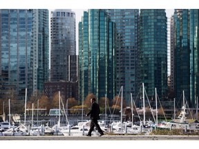 Coal Harbour condos are seen in the distance as a member of British Columbia Premier Christy Clark's security detail checks the area before her arrival for an announcement about shadow flipping in the real estate industry, in Vancouver, B.C., on Friday March 18, 2016.