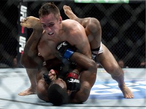Canada's Rory MacDonald pins Tyron Woodley of the United States to the mat during their welterweight bout at UFC 174 in Vancouver on June, 14, 2014.