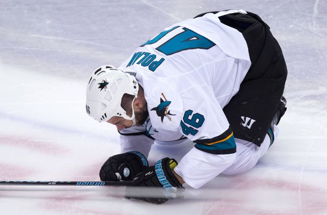 San Jose Sharks' Roman Polak, of the Czech Republic, kneels on the ice after being hit by Vancouver Canucks' Jake Virtanen during the second period of an NHL hockey game in Vancouver, B.C., on Tuesday March 29, 2016. (THE CANADIAN PRESS/Darryl Dyck)