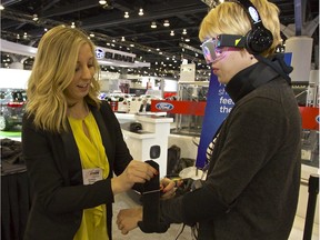 Ford of Canada representative Courtenay Rannard helps Vancouver Sun reporter Bethany Lindsay into a drugged driving suit Wednesday at the Vancouver International Auto Show.