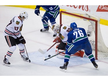 Chicago Blackhawks goalie Scott Darling, centre, stops Vancouver Canucks' Emerson Etem, right, as Blackhawks' Trevor van Riemsdyk watches during the second period of an NHL hockey game in Vancouver, B.C., on Sunday March 27, 2016.