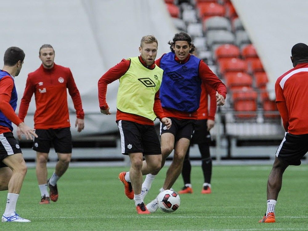 Scott Arfield (centre, in yellow bib) takes control of the ball during a Canada practice session on Tuesday in Vancouver.