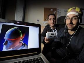 UBC psychiatrist Fidel Vila-Rodriguez (rear) is researching low-voltage electricity, administered by Parkinson's patients at home. He demonstrates here on Marlon Danilewitz.