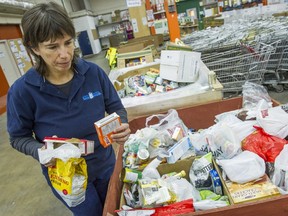 Ariela Friedmann, communications director of the Greater Vancouver Food Bank, inspects donations for past their best-before-dates, that are opened or damaged in Vancouver on Wednesday. Ric Ernst/PNG